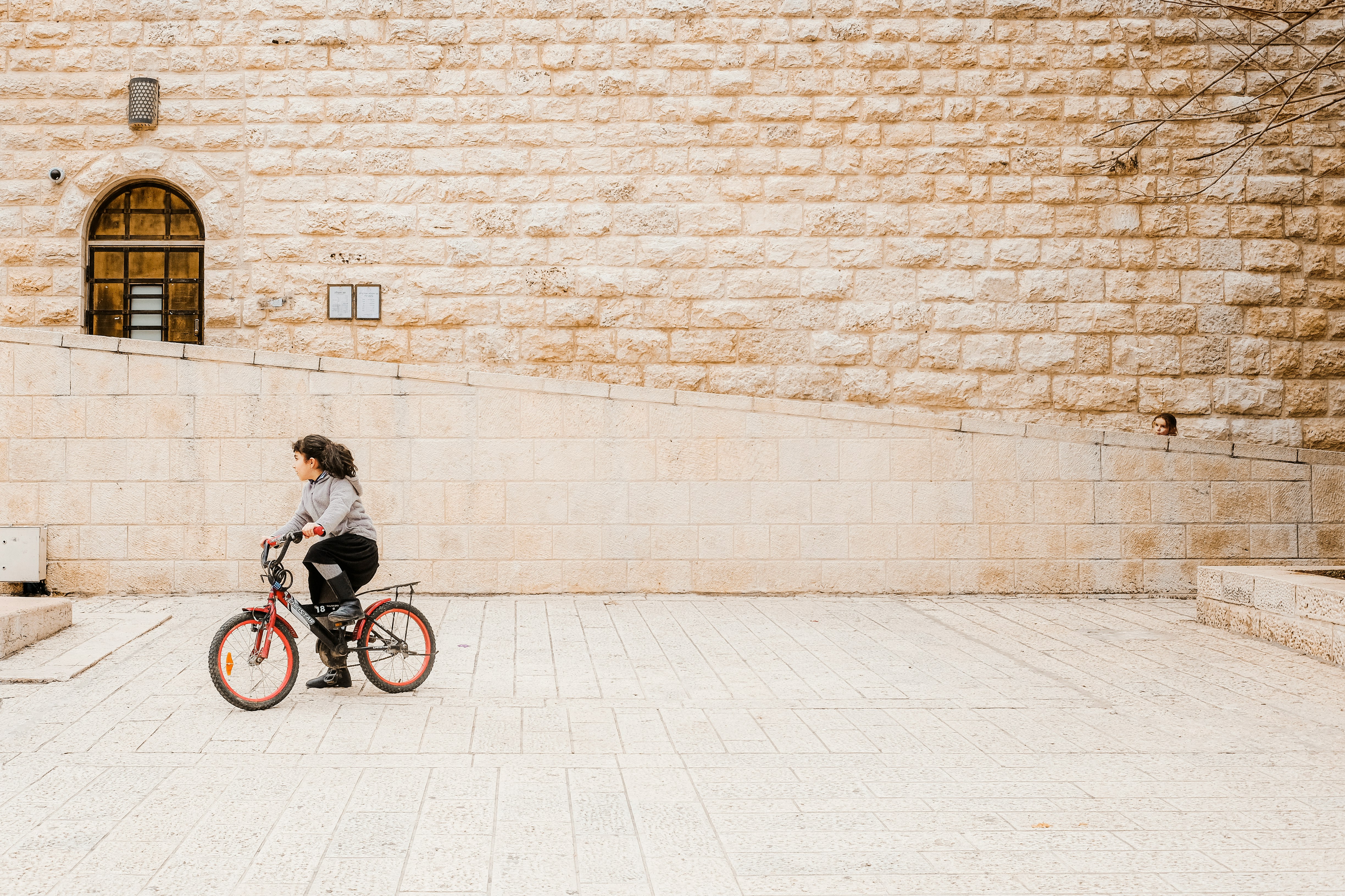 woman in black jacket riding on bicycle near brick wall during daytime